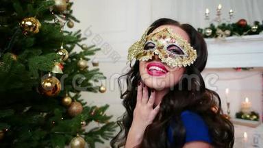 美丽的女孩戴着<strong>面具</strong>庆祝新年，圣诞<strong>化妆舞会</strong>，圣诞树附近的派对，一个年轻的女人穿着一件衣服